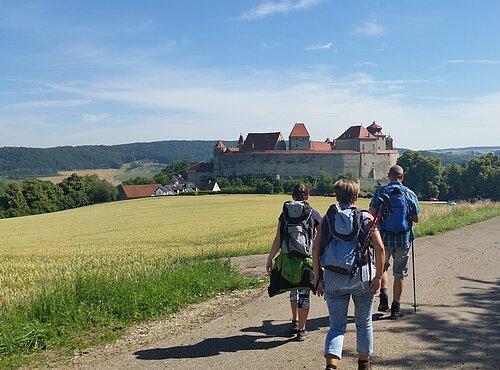 Wanderer unterwegs auf dem Bockrundweg. Im Hintergrund liegt die Harburg.