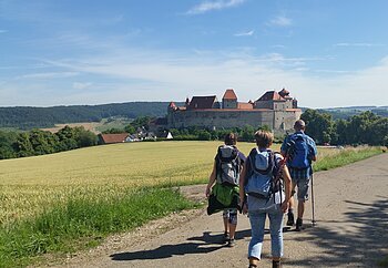 Wanderer unterwegs auf dem Bockrundweg. Im Hintergrund liegt die Harburg.