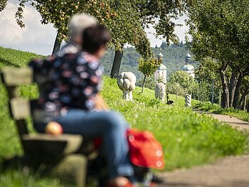 Zwei Wanderer auf einer Bank am Andachtsweg zur Wallfahrtsbasilika Maria Brünnlein.