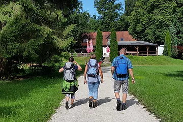 Wanderer auf den letzten Metern zur Einkehr in der Waldschänke Eisbrunn, die im Hintergrund zu sehen ist.