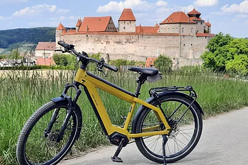 E-Bike auf einem Radweg bei Harburg. Im Hintergrund ist das Schloss Harburg zu sehen.