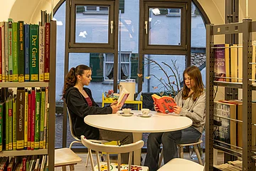 Zwei Mädchen lesen im Lesebereich der Bücherei