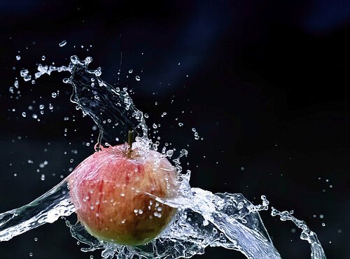 Apfel in der Luft, welcher von Wasser getroffen wird