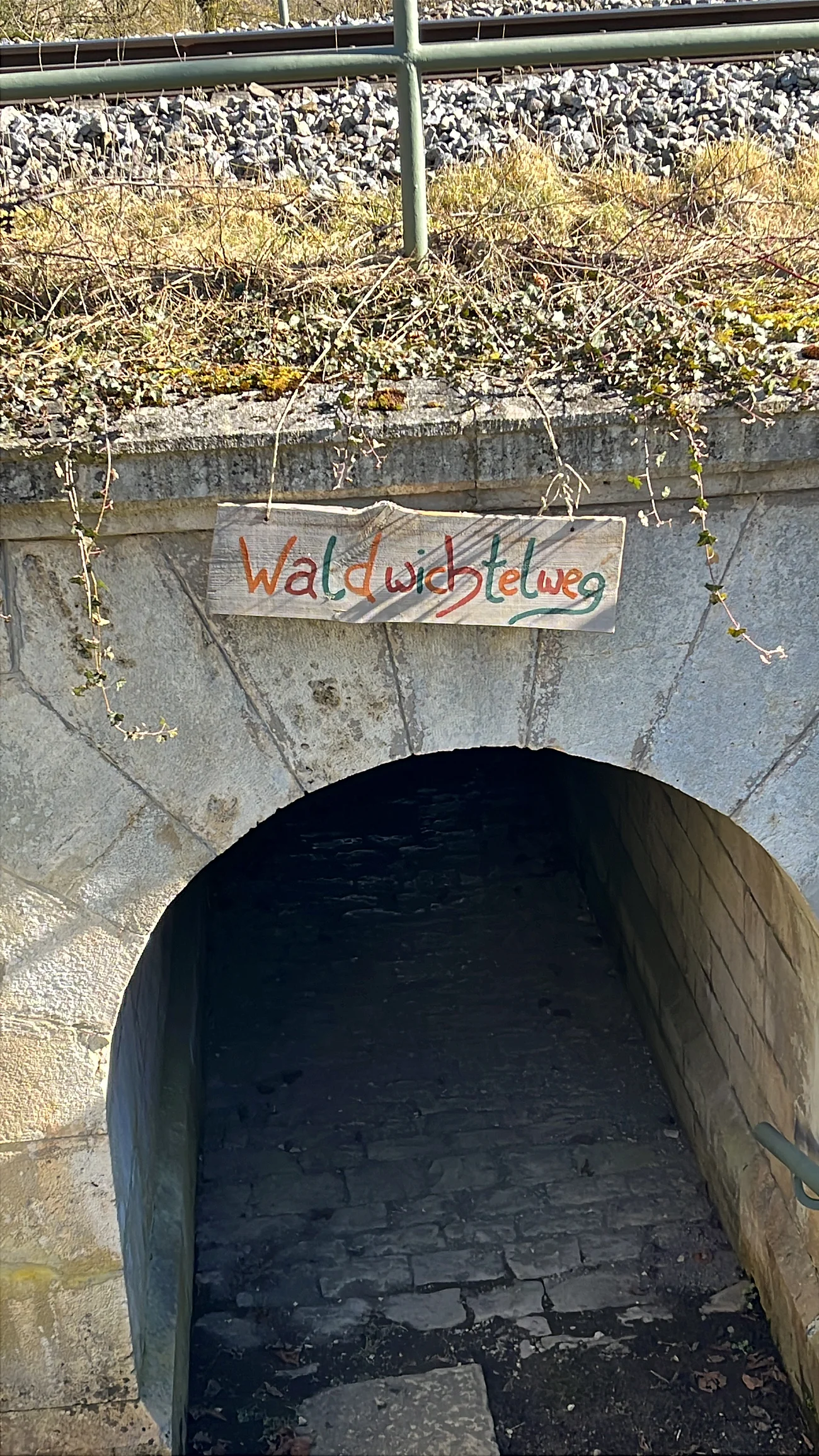 Wichtelweg Bild Eingang Der Wichtelwegeingang an einer Bahnbrücke mit einem Schild was den Weg weißt