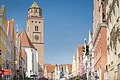 Reichsstraße Donauwörth Straßenszene mit bunten Gebäuden und einem Kirchturm im Hintergrund, Ampel im Vordergrund.