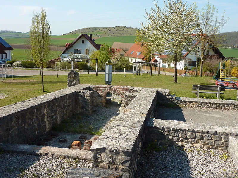 Ein Blick auf die Mauern des ehemaligen Römerbads in Großsorheim. Im Hintergrund sind ein Spielplatz und Wohnhäuser zu sehen.